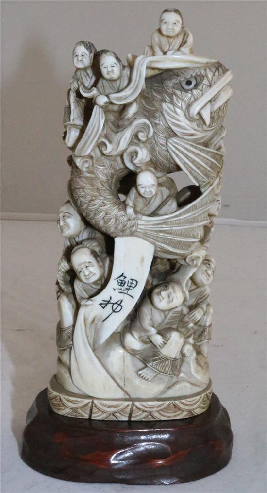 A Japanese walrus ivory okimono of men holding a giant carp, early 20th century, 15cm, wood stand